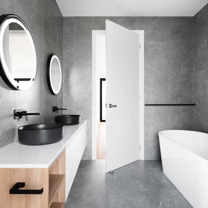 Bathroom interiors with a bathtub and dark ceramic tiles on the walls of the bathroom.